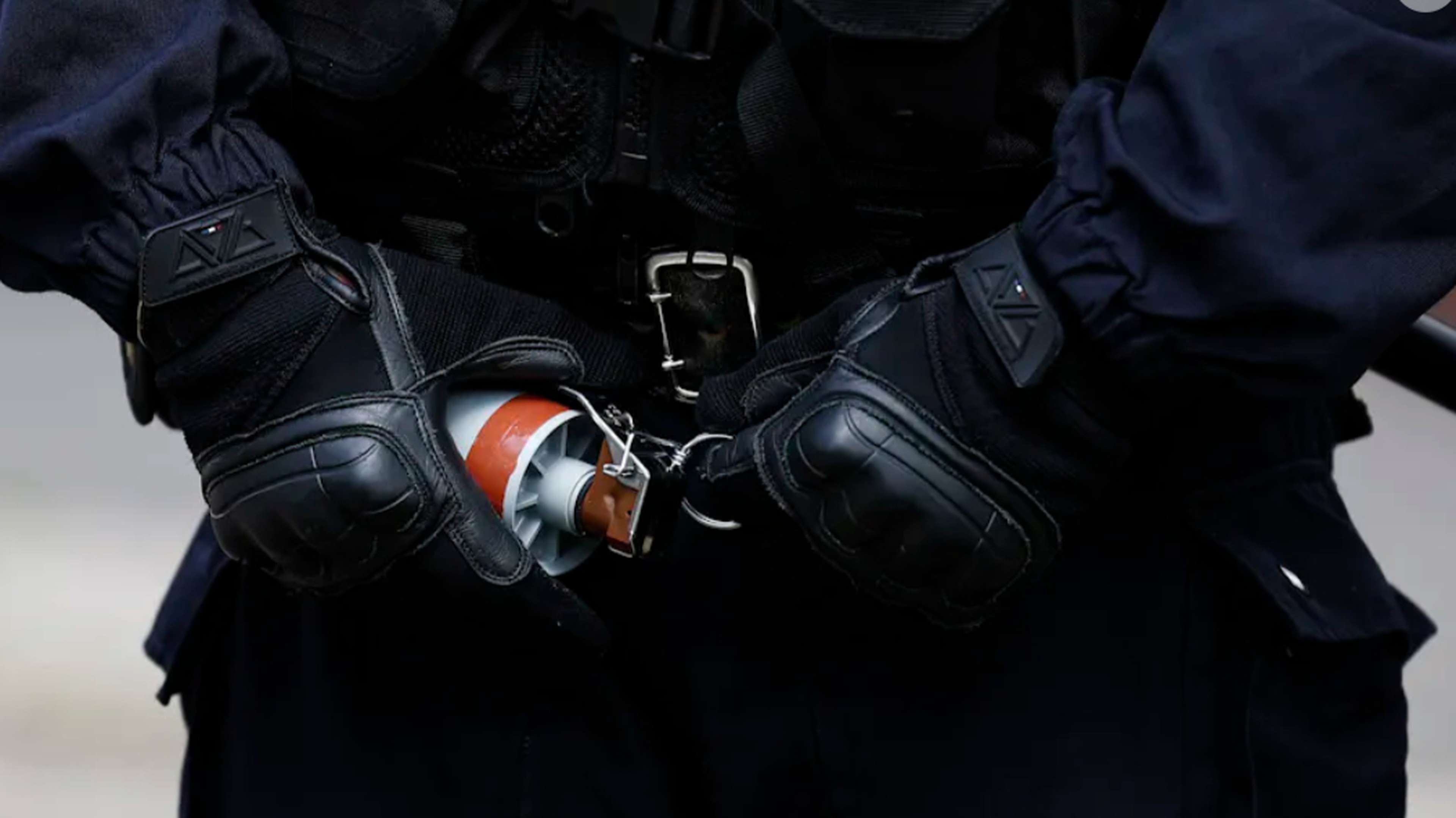 Un policier s’apprête à utiliser une grenade de désencerclement